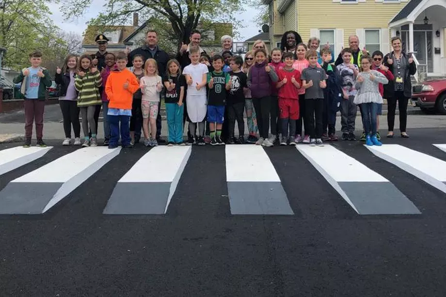A street art design that makes the bars in a crosswalk appear 3D.