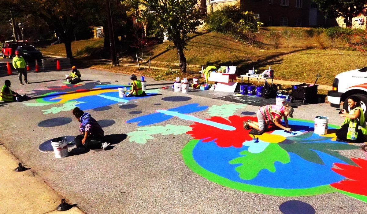 Artists from Chalk Riot paint asphalt art on Bunker Hill Road outside Joe's Movement Emporium. 