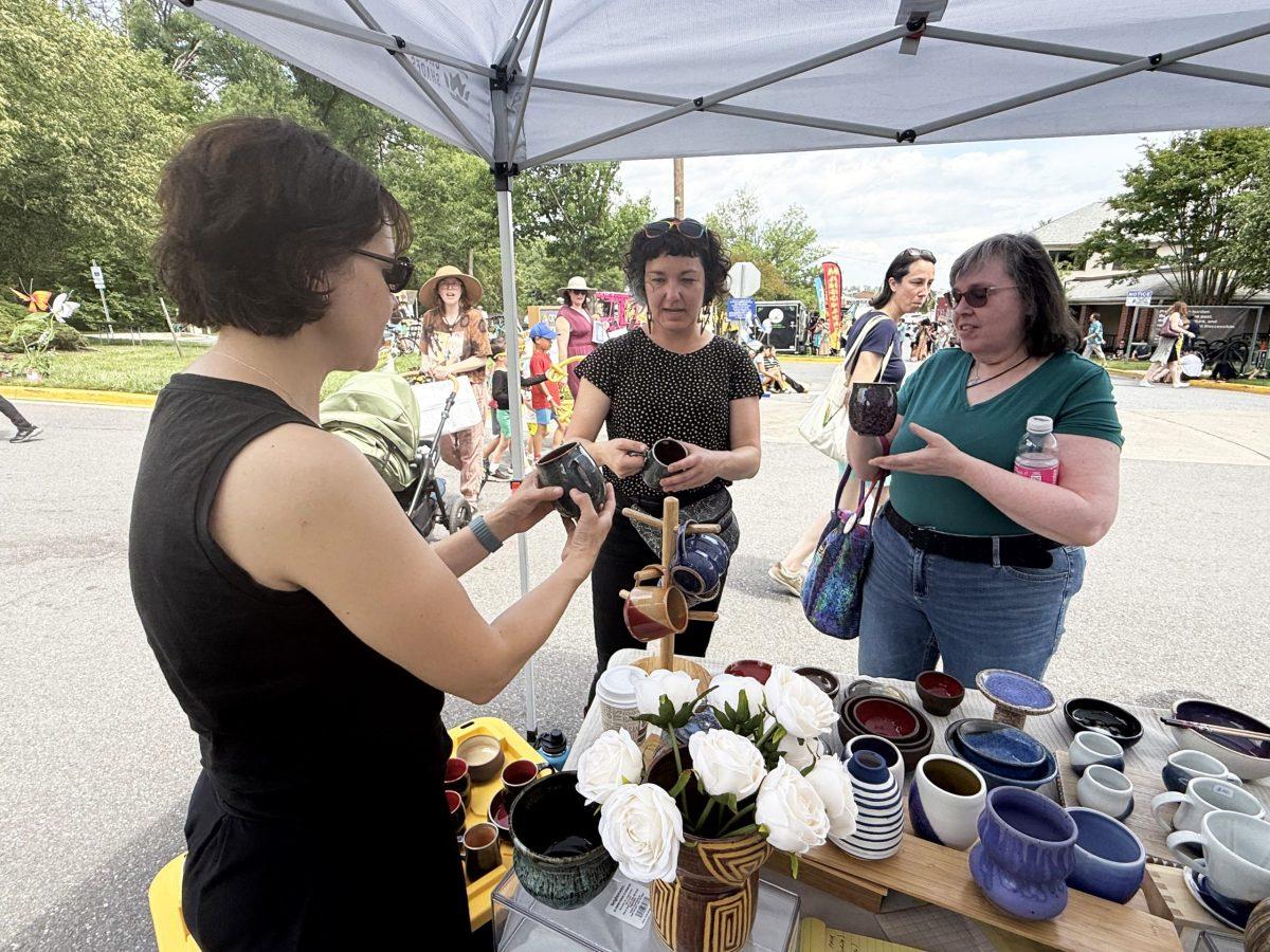Eileen Arnold, a resident of College Park’s Autoville neighborhood (right) and Jess Eliot Myhre, whose band performed at the Spring Street Fair, admire pieces at a booth called Omphalos Pottery. Photo by SHARON O'MALLEY